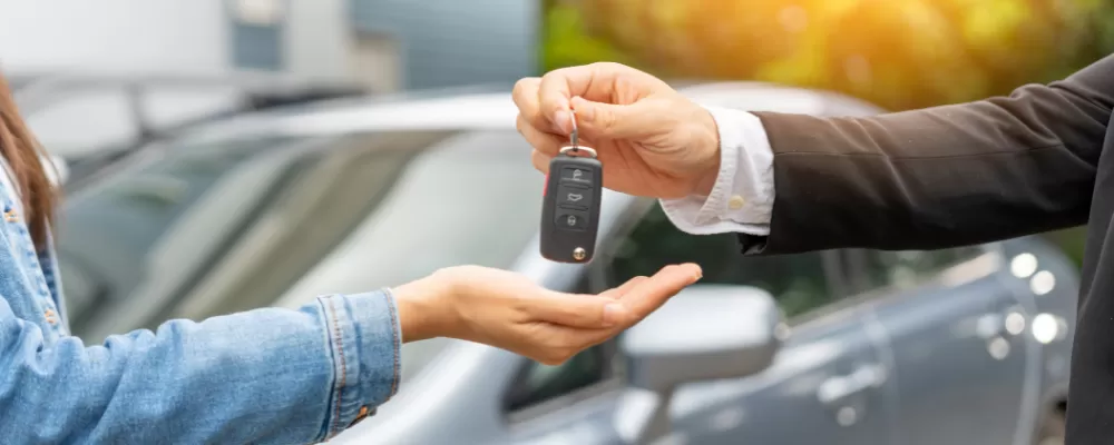 What's the difference between financing and lasing a car - Image of a couple shaking hands with a car dealer